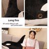 A black and white lifelike orca whale plush toy with long fins is shown next to a person reading a book.