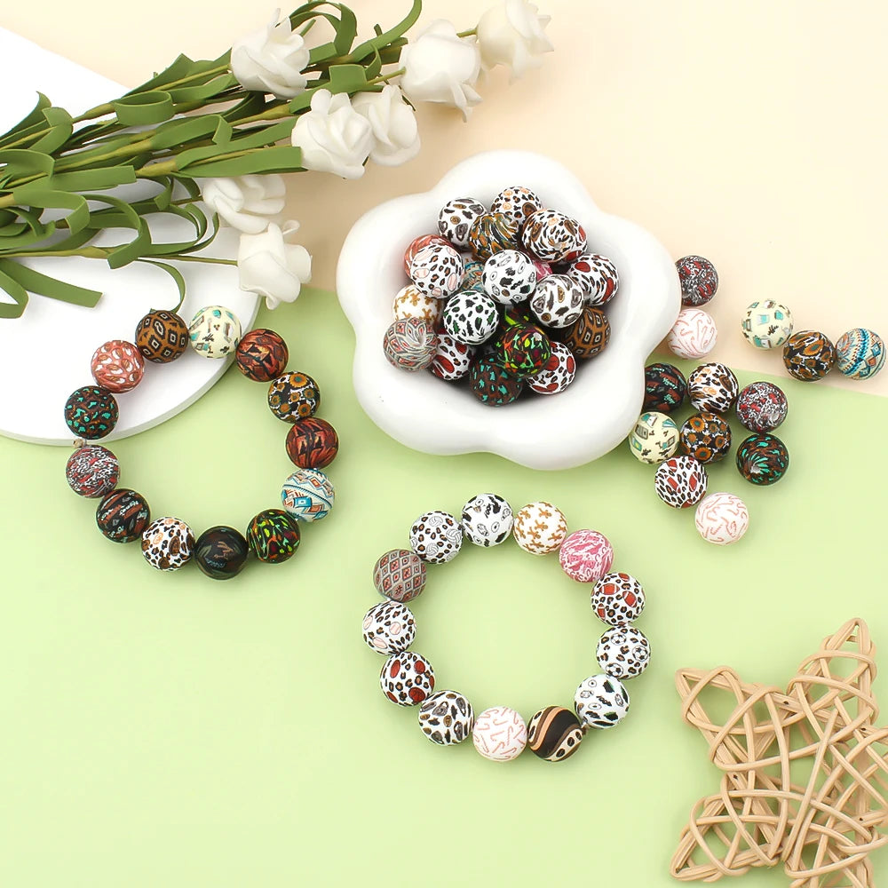 A collection of colorful printed silicone beads in various patterns and colors arranged around a white bowl and greenery.