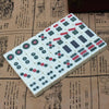 A rectangular grid of Mahjong tiles featuring various colored discs on a light background, resting on aged paper.