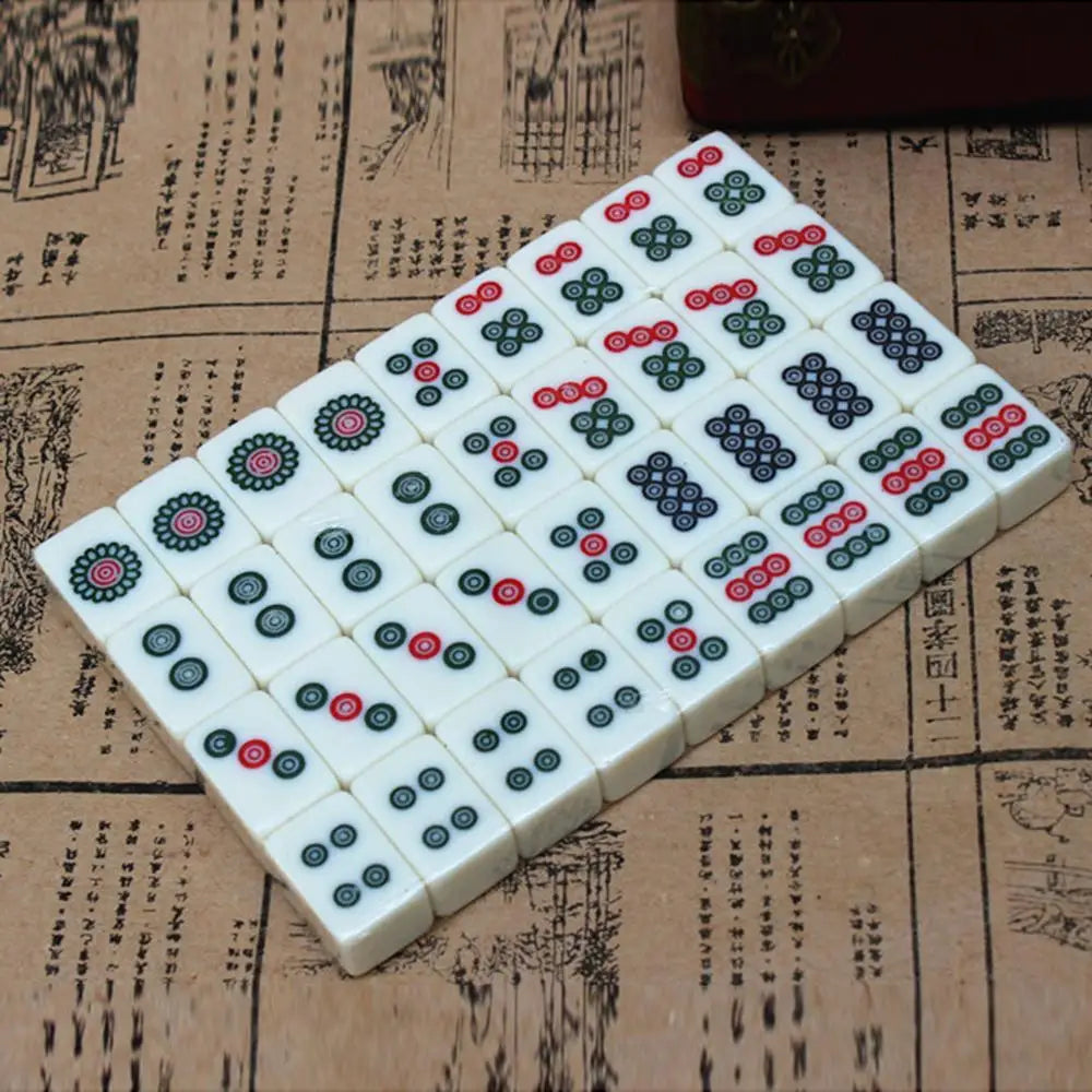 A rectangular grid of Mahjong tiles featuring various colored discs on a light background, resting on aged paper.