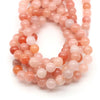 A strand of round rose quartz beads in shades of pink and peach for jewelry making.