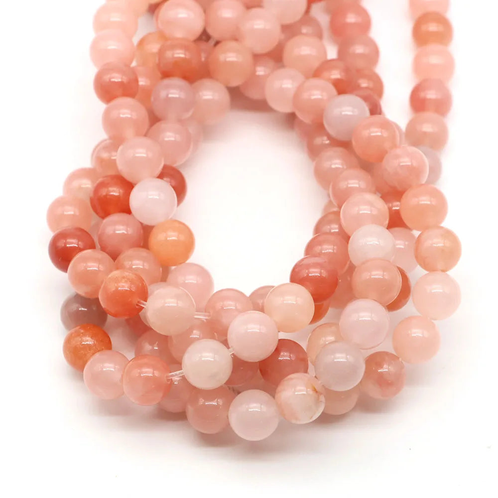 A strand of round rose quartz beads in shades of pink and peach for jewelry making.
