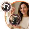 A woman holds a finished Halloween diamond painting hanging ornament kit featuring a black cat surrounded by colorful jewels.