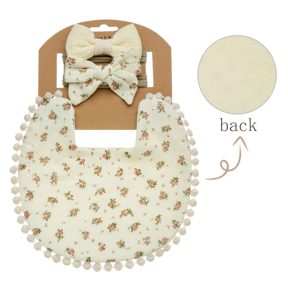 A set of baby flower bib and headband featuring a light cream fabric with pink floral patterns.