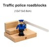 A wooden traffic police roadblock figurine with a white barrier, used as a train track accessory.