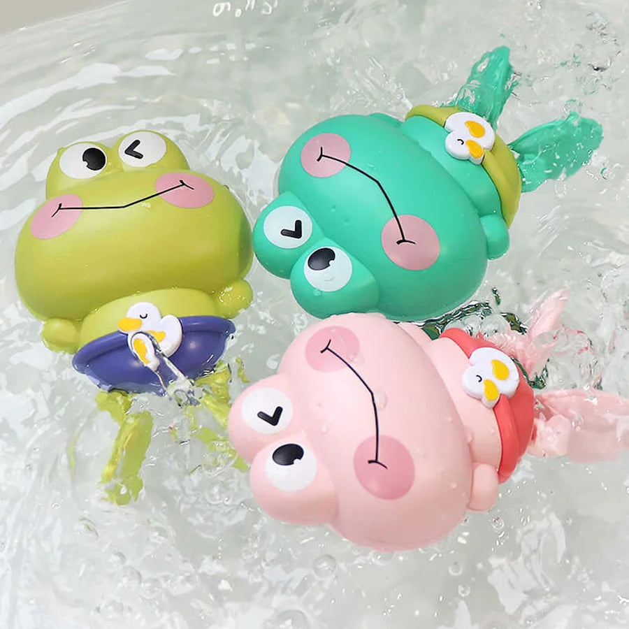 A set of three plastic frog bath toys in lime green, teal, and pink floating in water.