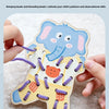 A hand is holding a wooden elephant lacing toy with purple beads and stringing threads on a soft, white surface.