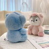 A soft blue husky plush toy next to a pink fluffy bear plush toy on a white surface.