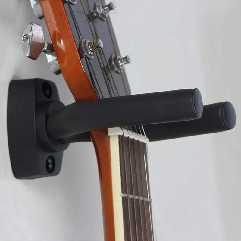 A black guitar wall mount hanger with soft padding is shown attached to a wooden guitar neck.
