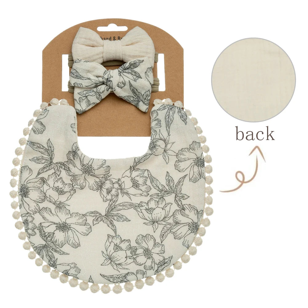 A beige baby flower bib and headband set with a floral pattern shown next to its packaging.