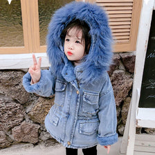 A child wearing a blue denim jacket with a faux fur collar posing for a photo.