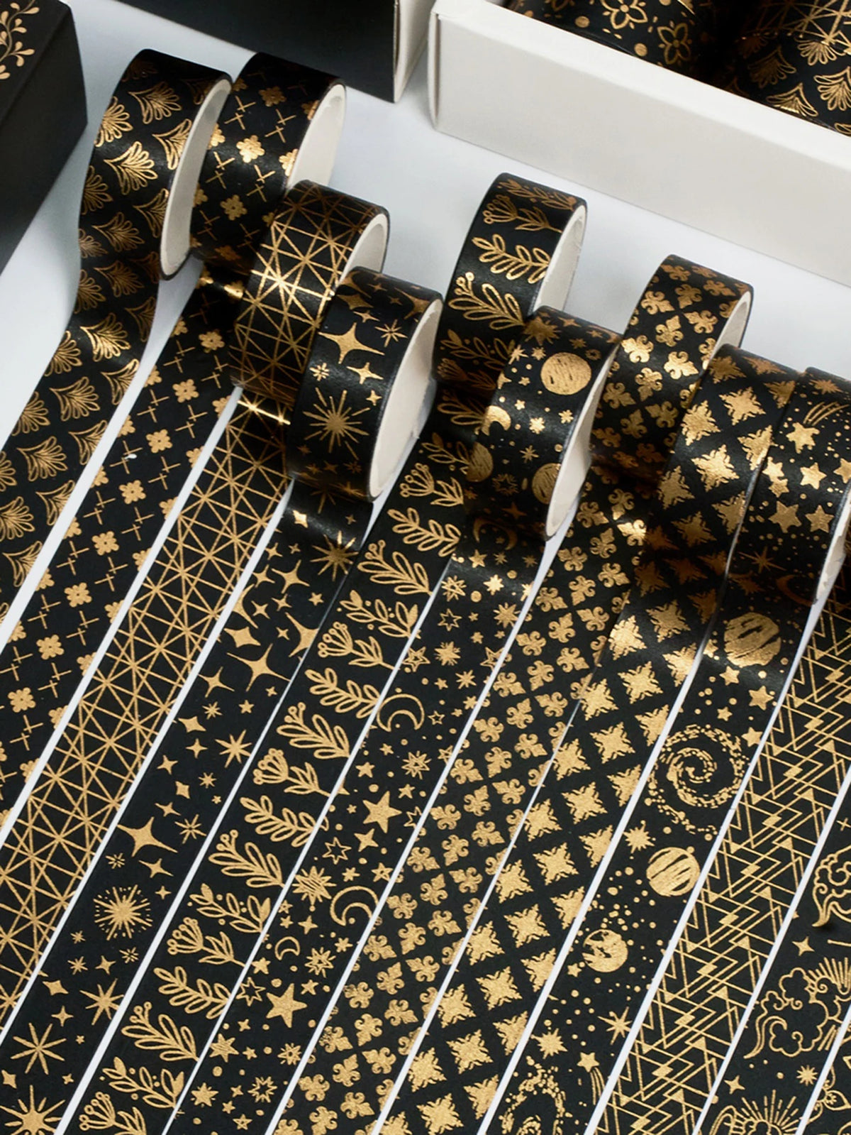 A set of twenty rolls of black and gold foil washi tape, featuring intricate patterns like stars and foliage.