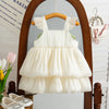 A white sleeveless pleated princess dress for a baby girl displayed on a wooden hanger.