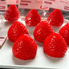 A collection of bright red strawberry squishy toys arranged on a white plate.