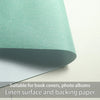 A close-up view of a light green linen surface and backing paper material.