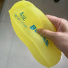 A hand holds a yellow moldable butter stick squishy stress relief toy labeled 4oz net wt.