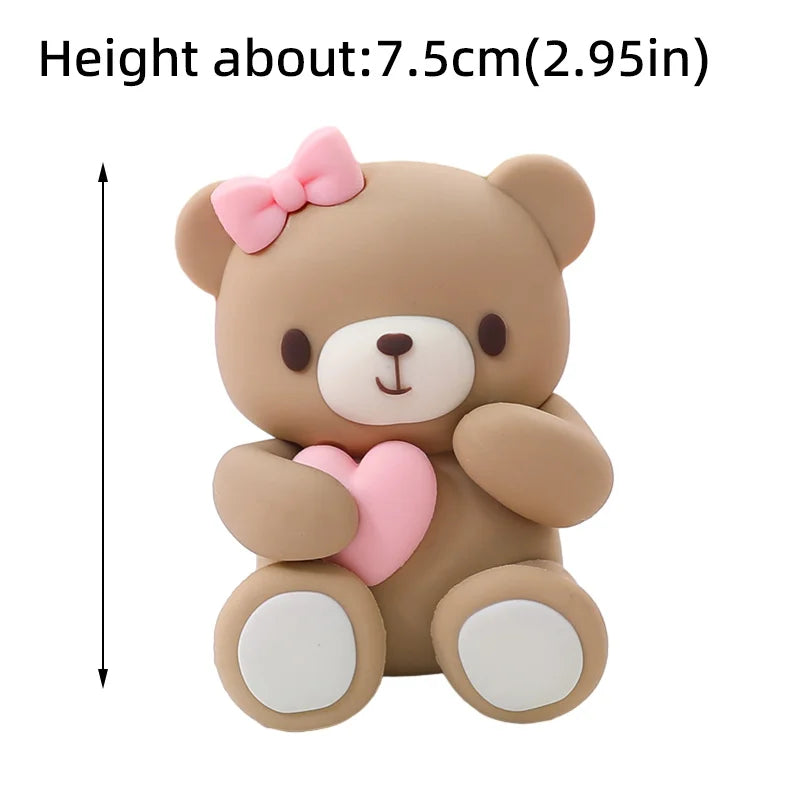 A cute, light brown bear-shaped cake topper with pink accents and a bow.