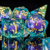 A close-up of a set of iridescent, translucent blue and purple liquid core dice for tabletop gaming.