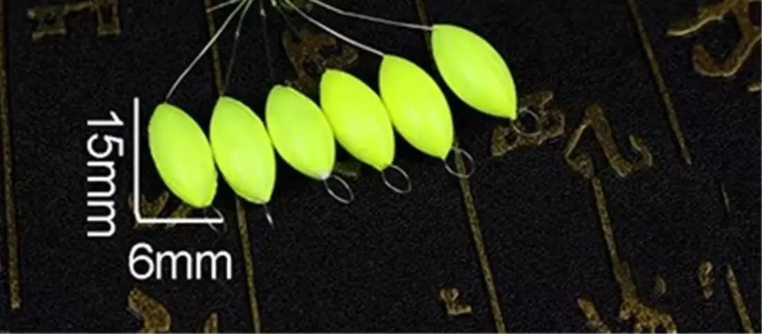 A row of bright yellow oval fishing floats with attached bobber beads are displayed against a dark background.