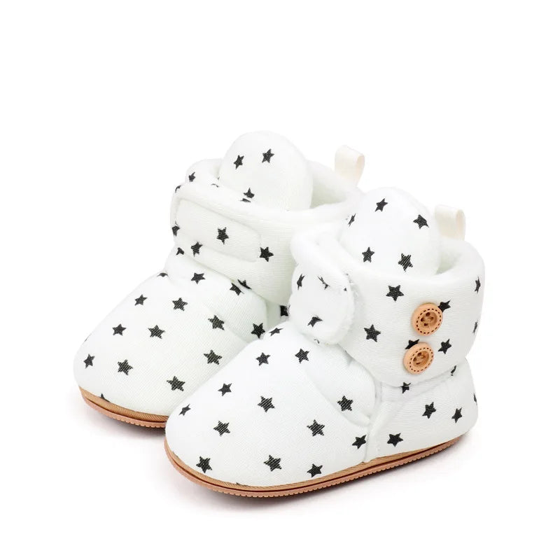 White baby winter snow boots with fuzzy ball accents featuring black star patterns