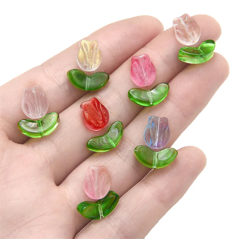 A hand displays various gradient colored tulip glass beads for jewelry making