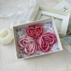 A white box contains pink heart-shaped flower silicone molds surrounded by shredded white material.
