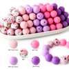A collection of soft food-grade silicone beads in various shades of pink and purple arranged on a white plate.