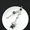 Silver and pearl keychain featuring a black charm shaped like an anime character.