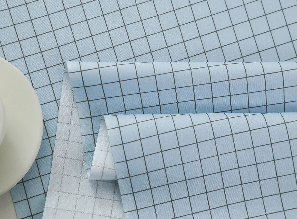 Light blue grid print fabric rolled and stacked for sewing and DIY crafts