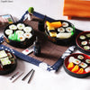 A set of miniature Japanese sushi rolls and ingredients arranged on a wooden board for a dollhouse kitchen display.