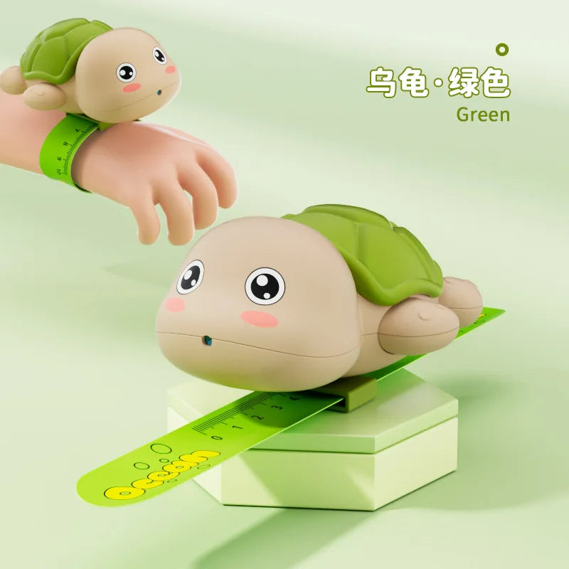A green turtle-shaped water gun is shown next to a hand, with a ruler for scale.