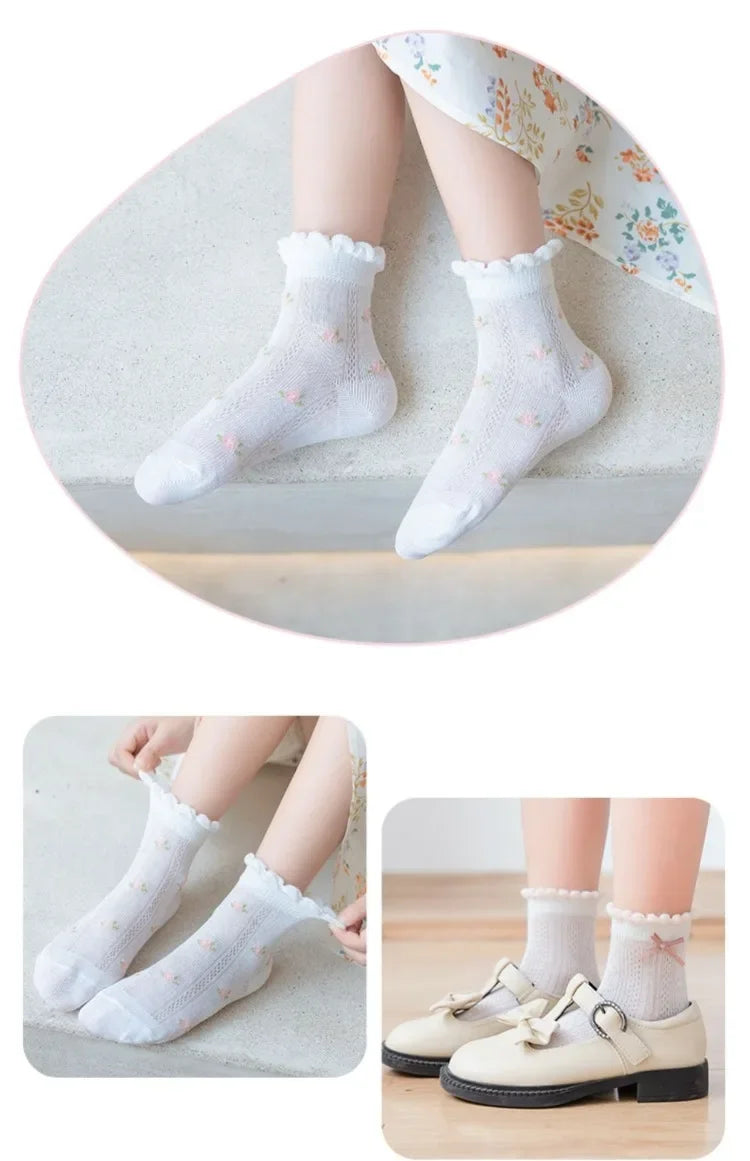 A pair of white floral cotton kids socks worn on a foot, displayed next to a pair of shoes.