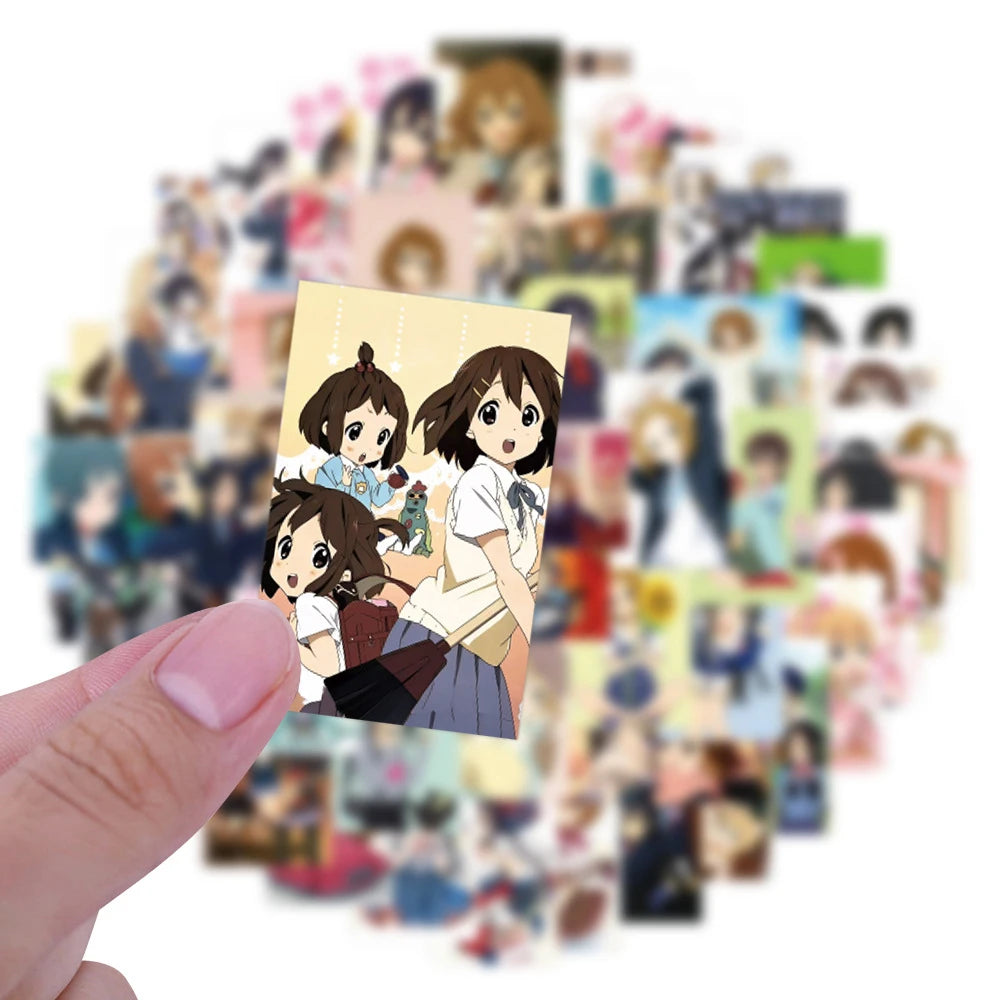 A hand holds a sticker pack featuring cute K-ON! anime characters and guitar girl decals.
