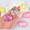 A hand holds several iridescent heart-shaped squishy toys in shades of yellow, pink, and purple foam.