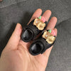 A hand holds a pair of brown fashion slippers with pink accents for 1/6 BJD dolls.