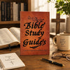 A leather-bound Bible Study Guide book resting on a wooden table next to an open Bible and a notebook.