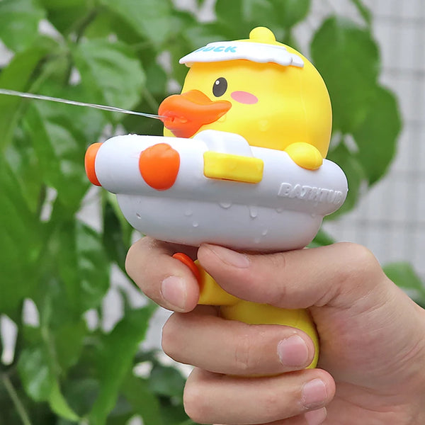 A hand holds a yellow duck shower toy with an orange beak and white body against a blurred green background.