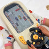 A child is holding a yellow and black interactive steering wheel driving toy with sound effects on a white surface.