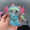 A hand holds a translucent blue squishy axolotl stress relief toy with pink fins and glitter.