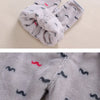 A gray fleece jacket and pants set for a baby with black mustache cartoon prints.
