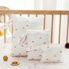 A set of three white waterproof bags for swimsuits, diapers, and travel items placed on a marble surface.
