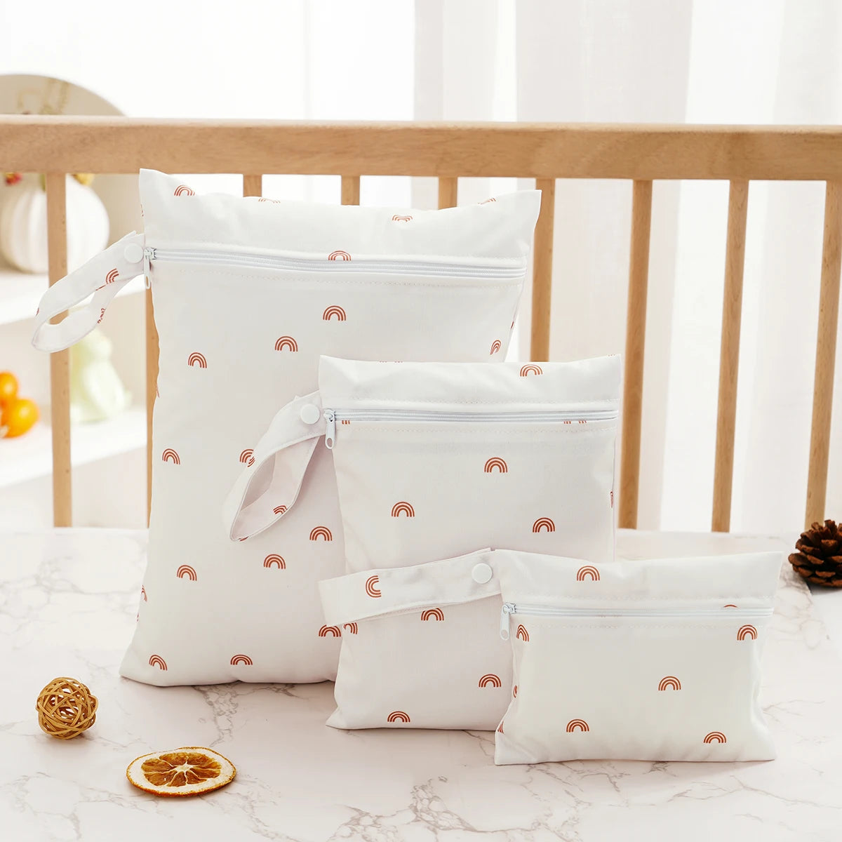 A set of three white waterproof bags for swimsuits, diapers, and travel items placed on a marble surface.