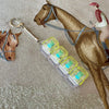A brown horse figurine is shown with a clear acrylic keycap fidget keychain attached to its bridle.