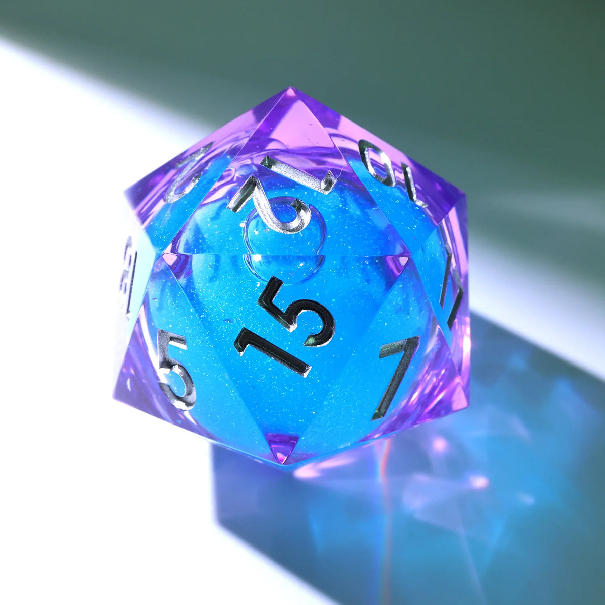 A handmade resin D20 die with a large blue and purple liquid swirl, viewed at an angle.