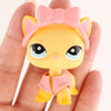 A small yellow cat figure with pink ears and a pink bow is held in a person's hand.
