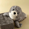 A gray seal plush toy resting on a textured, cylindrical surface.
