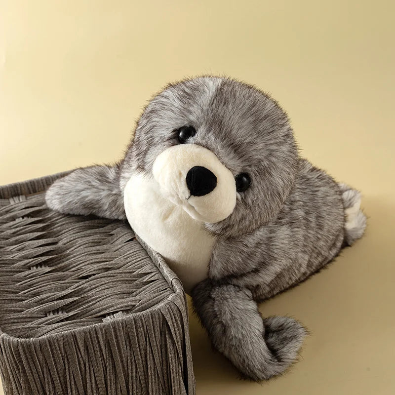 A gray seal plush toy resting on a textured, cylindrical surface.