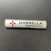 Silver metal badge with an umbrella emblem and the text UMBRELLA CORPORATION