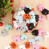 A pile of colorful ghost silicone beads in various shades including pink, black, orange, and light blue on a wooden surface.