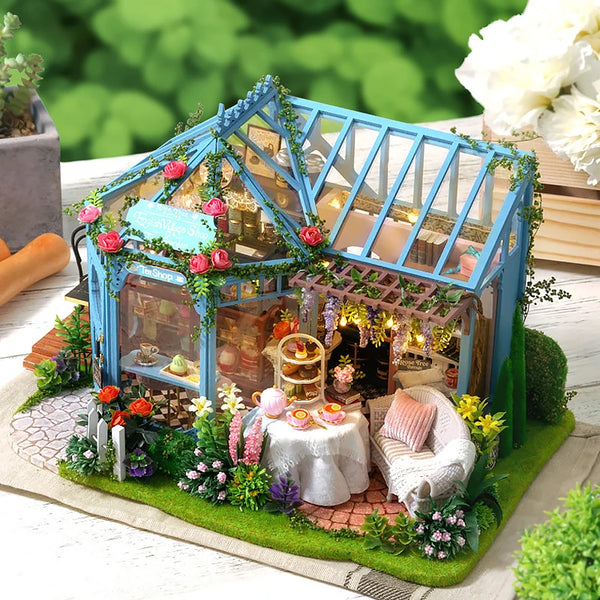 A detailed wooden dollhouse kit featuring a blue structure, furniture, and decorative lighting set in a miniature garden scen